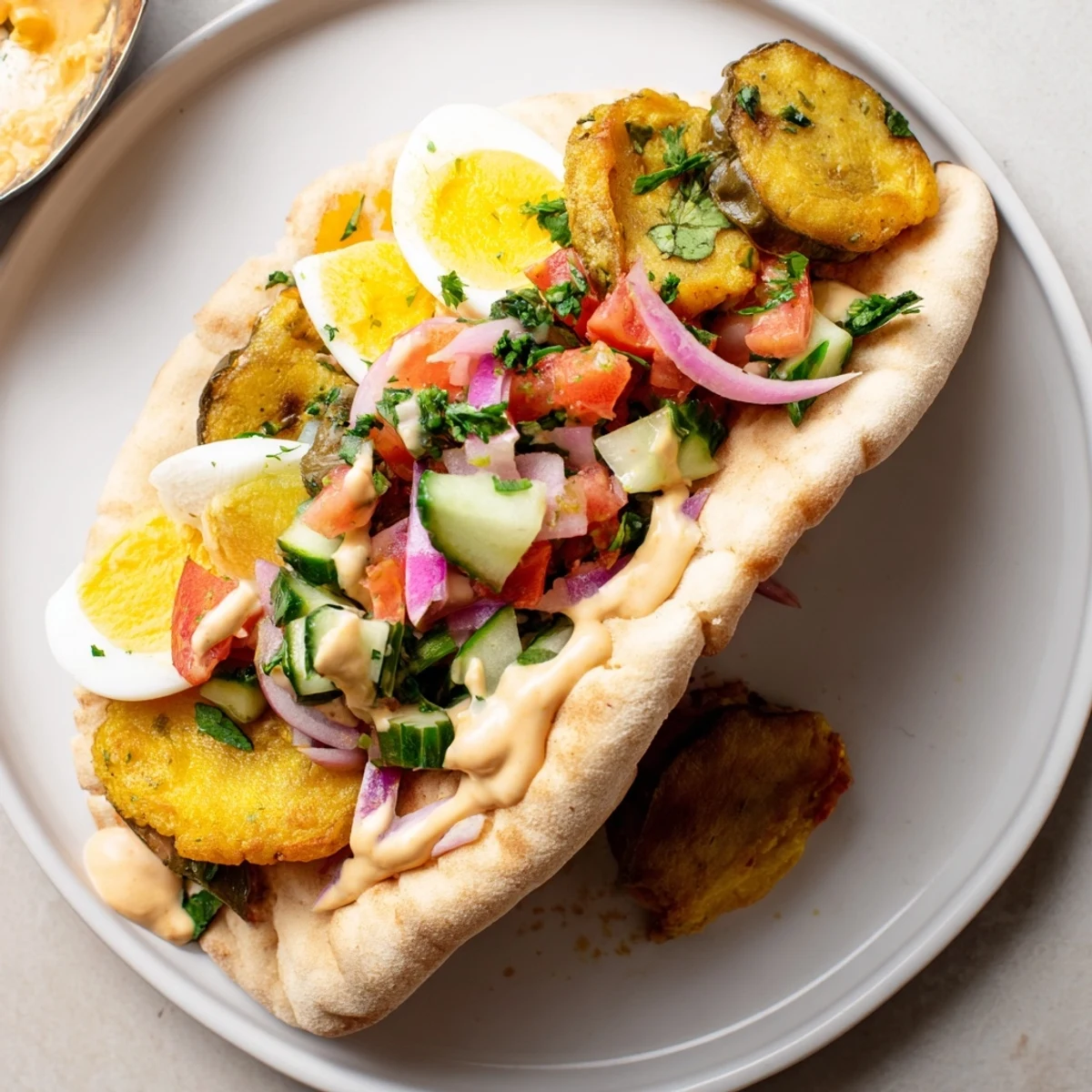 Golden fried eggplant and vibrant Israeli salad bursting from a hearty Israeli Sabich.
