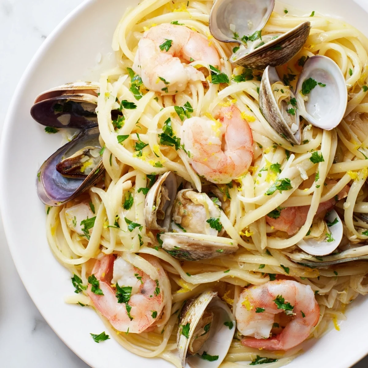 Tender linguine is tossed with juicy shrimp, briny clams, and mussels in a lemony white wine garlic sauce, with steam rising from the warm pasta.