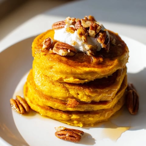 Golden-brown fluffy pumpkin spice pancakes piled high, ready to be drizzled with syrup.