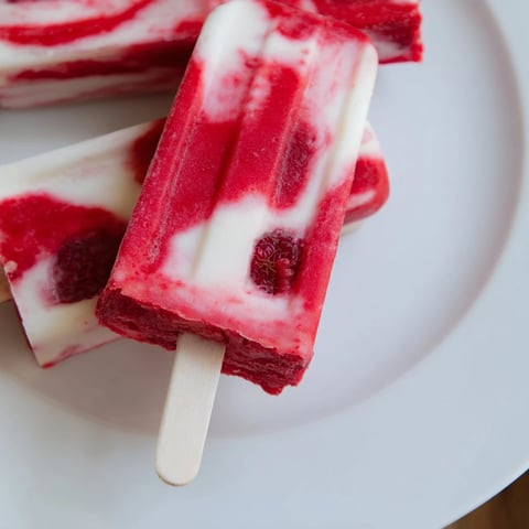 Creamy, layered Raspberry Coconut Ice Pops, bursting with fresh raspberries and dairy-free coconut.