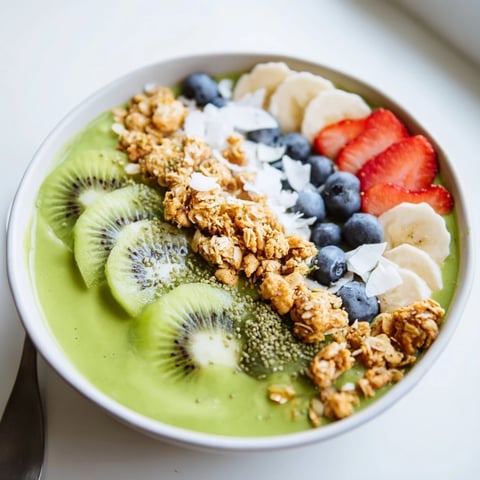 Green Smoothie Bowl topped with crunchy granola and fresh kiwi slices for a vibrant, healthy breakfast.  