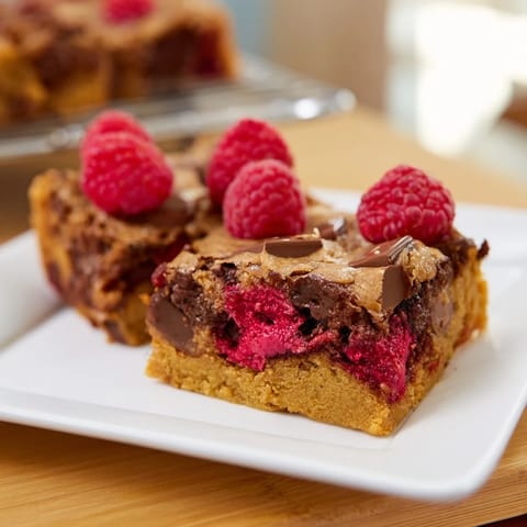 Freshly baked blondies with white chocolate and raspberries: a close-up of the delicious, golden treat.