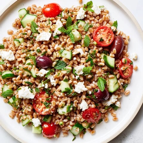 Close-up of nutty farro salad with red onion, parsley, and crumbled feta, ready as a refreshing vegetarian side dish for summer gatherings.