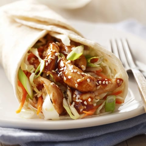 A close-up of a Teriyaki Chicken Wrap, filled with tender chicken and fresh vegetables, served for lunch.