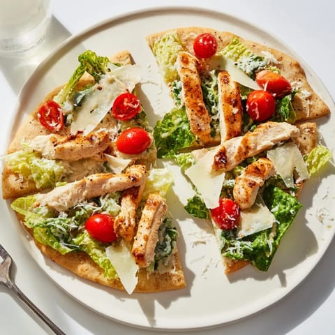 Savory Caesar Chicken Flatbread with fresh romaine, Parmesan, and lemon wedges, ready to serve on a rustic wooden table.  