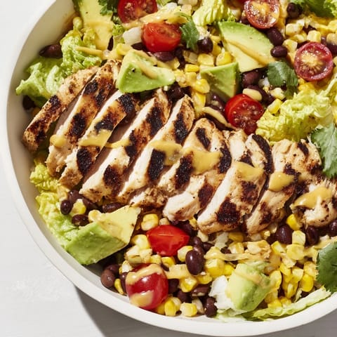 A close-up of grilled honey lime chicken slices topping a colorful taco salad drizzled with tangy dressing.