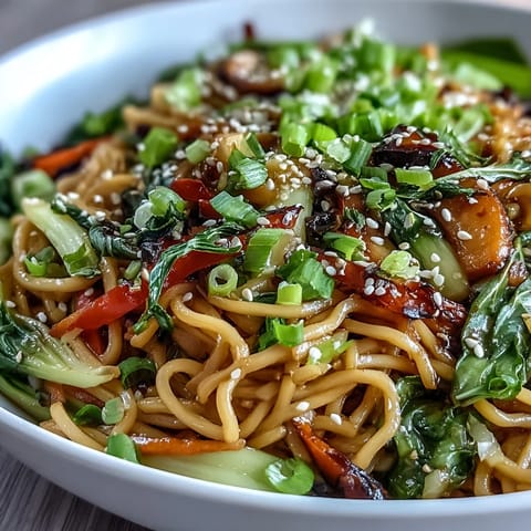 Shirataki Noodle Bowl garnished with toasted sesame seeds and fresh cilantro, served with chopsticks on a wooden table.