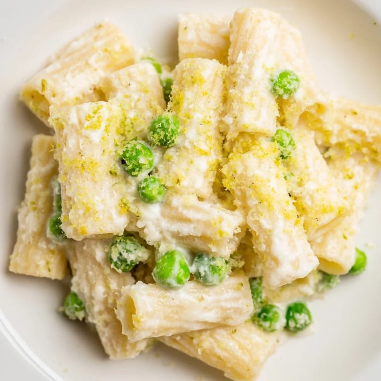 A vibrant bowl of Pea & Lemon Ricotta Pasta topped with grated Parmesan and bright lemon zest.  