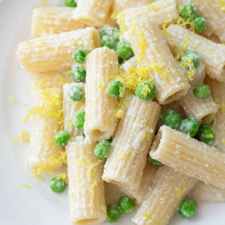 Spring-inspired Pea & Lemon Ricotta Pasta with al dente rigatoni, green peas, and herby basil garnish.