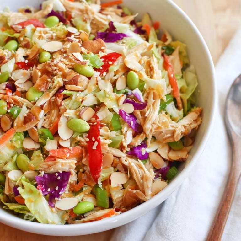 Serving suggestion for Edamame Crunch Chicken Salad: crisp greens topped with roasted cashews and sesame seeds, paired with iced green tea.